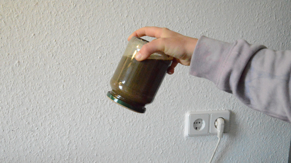 Glas mit Erde-Wasser-Gemisch schütteln
