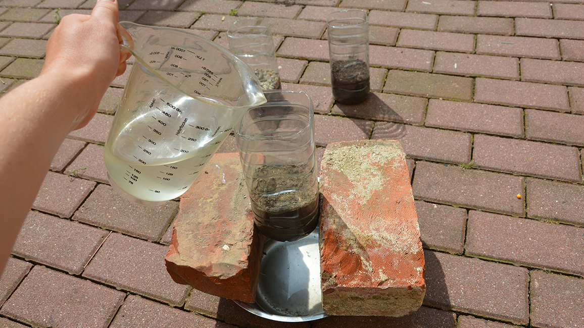 Wasser in Flsche mit Erdprobe füllen.